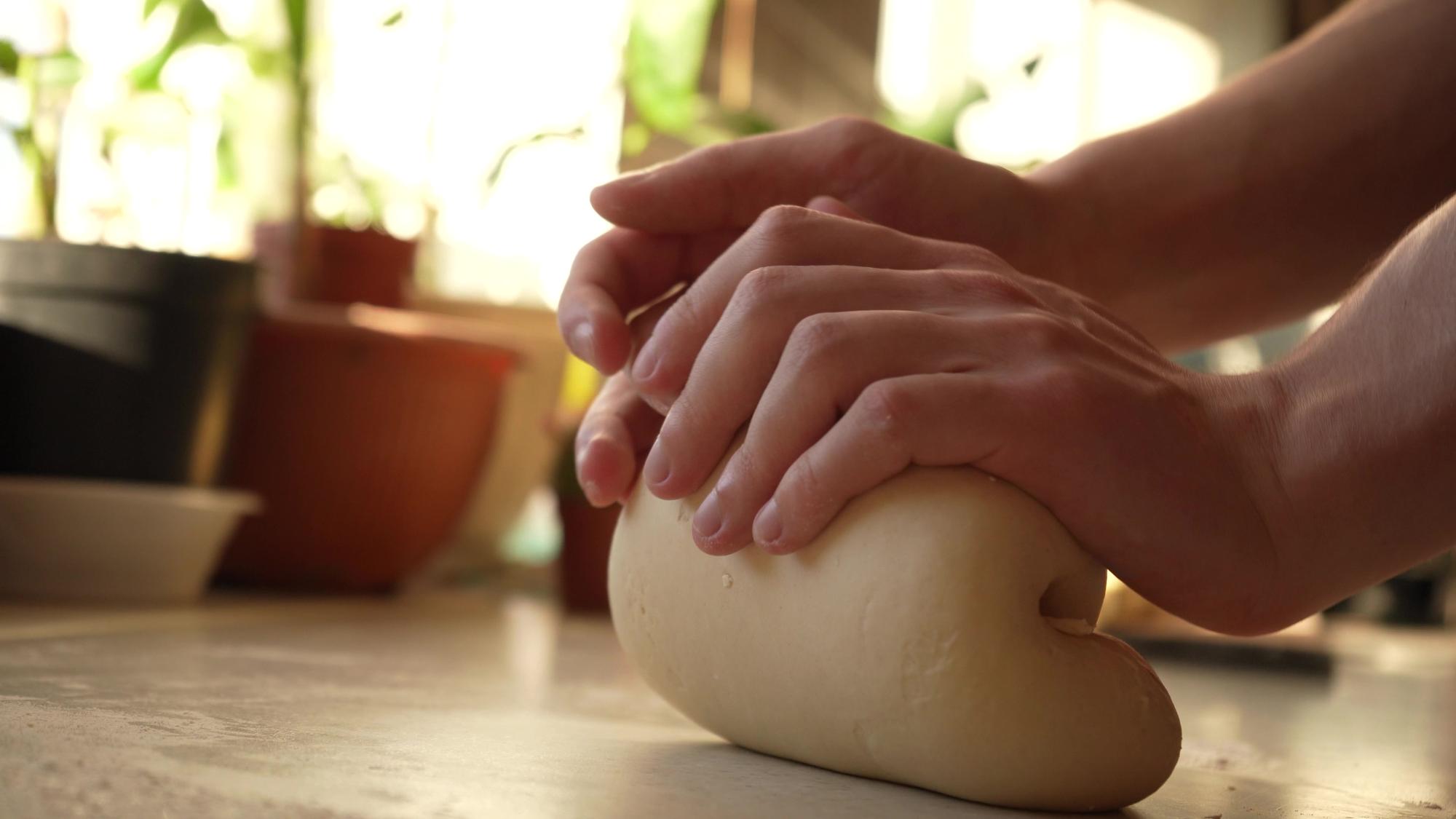 Hands kneading dough on floured board